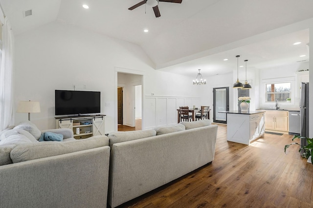 living area with light wood-type flooring, visible vents, vaulted ceiling, and ceiling fan with notable chandelier