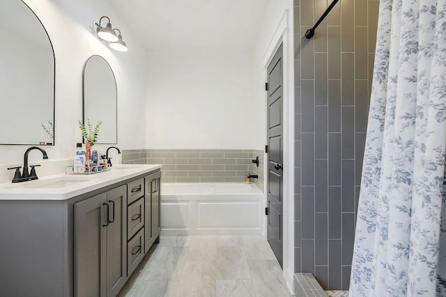 full bathroom with double vanity, a garden tub, a shower stall, and a sink