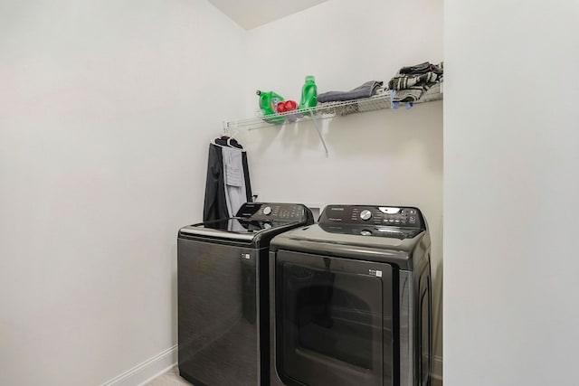 washroom featuring washing machine and dryer, laundry area, and baseboards