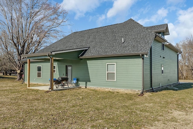 back of property featuring a patio area, a yard, and roof with shingles