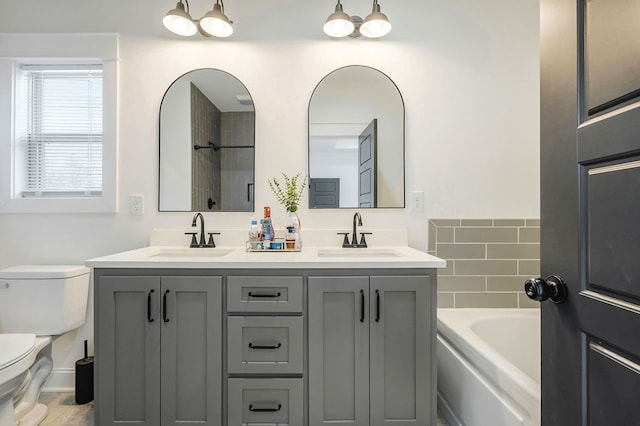 bathroom featuring double vanity, a bathing tub, a sink, and toilet