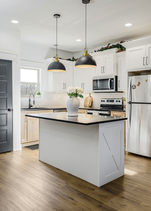 kitchen with stainless steel appliances, dark countertops, decorative light fixtures, and white cabinets