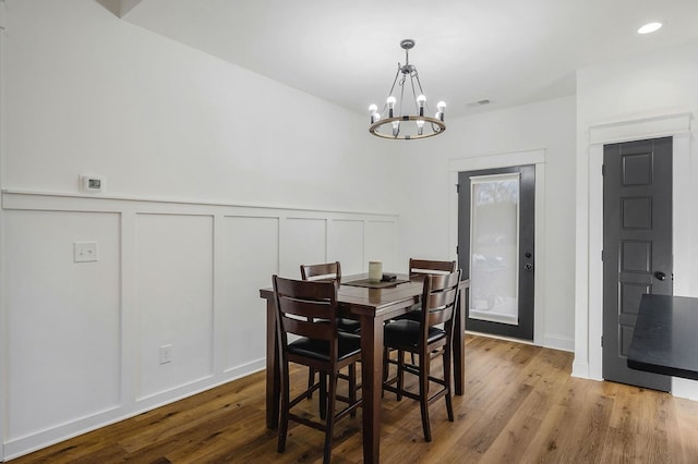 dining room featuring wainscoting, a notable chandelier, a decorative wall, and light wood finished floors