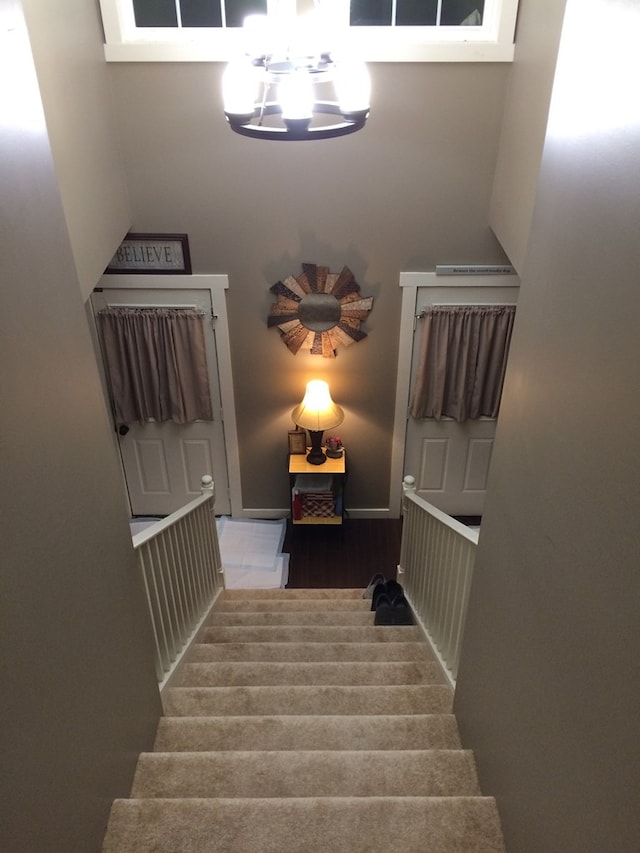 staircase with a notable chandelier and a towering ceiling