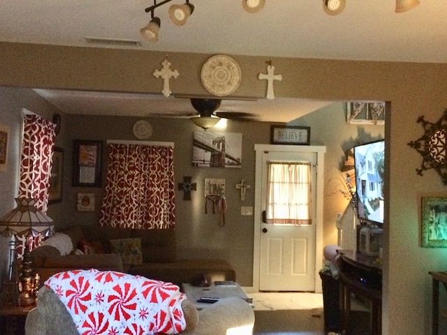 living area with visible vents and ceiling fan