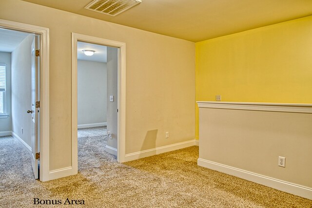 spare room with baseboards, visible vents, and light colored carpet