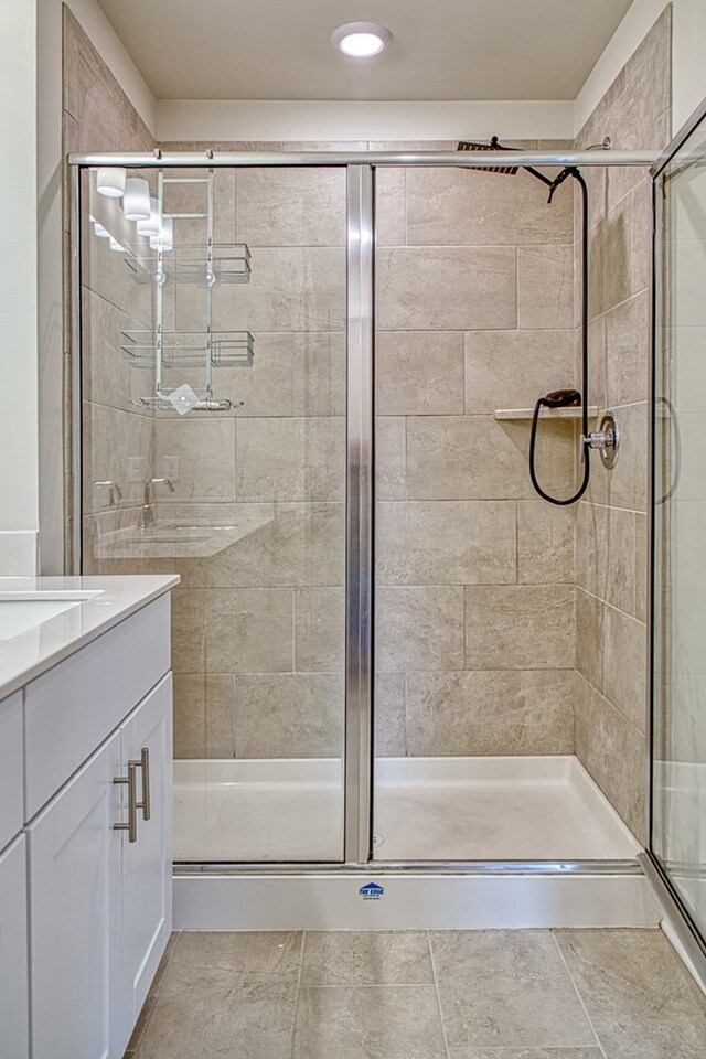 bathroom featuring tile patterned flooring, a shower stall, and vanity