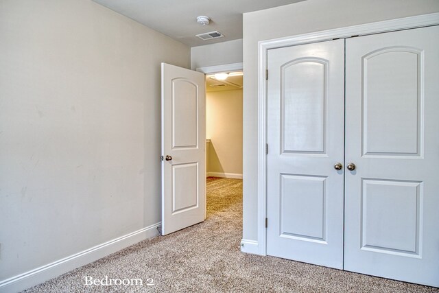 unfurnished bedroom with light carpet, a closet, visible vents, and baseboards