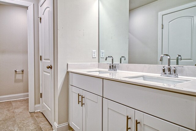 full bathroom featuring double vanity, a closet, a sink, and baseboards