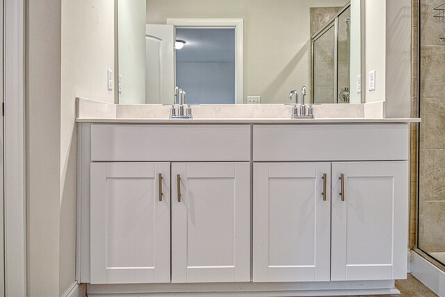 bathroom featuring a sink, a shower stall, and double vanity