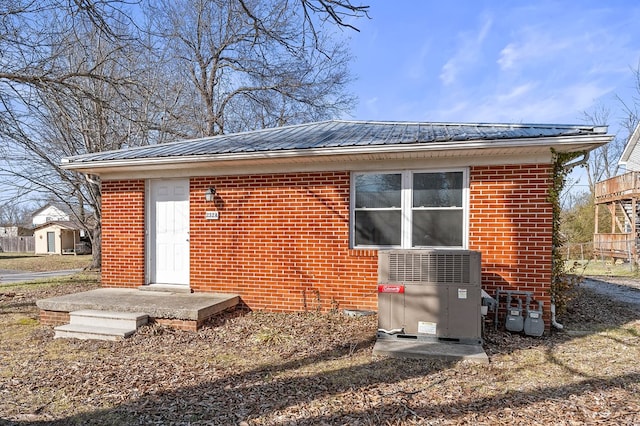 exterior space with metal roof, brick siding, and cooling unit