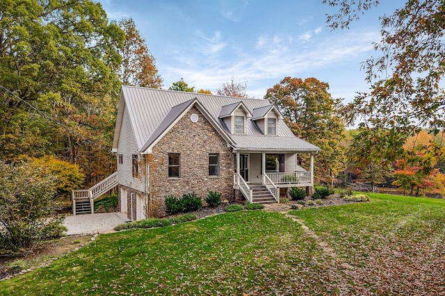 view of front of home featuring stairs, metal roof, covered porch, and a front yard