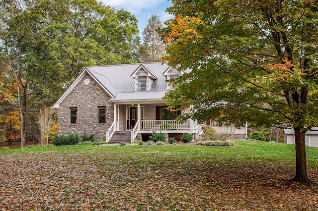 view of front facade featuring stone siding, metal roof, a porch, and a front yard