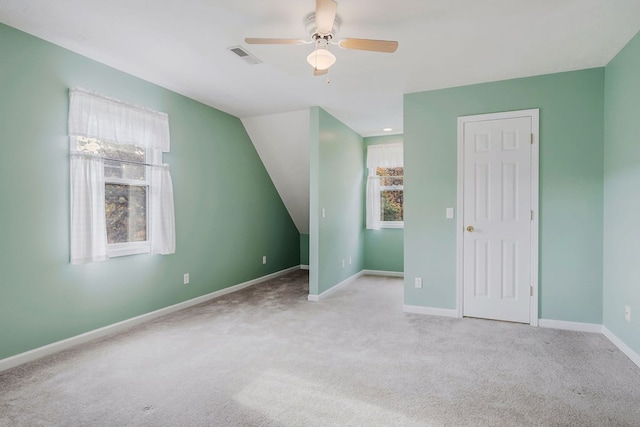 additional living space featuring a healthy amount of sunlight, baseboards, visible vents, and light colored carpet