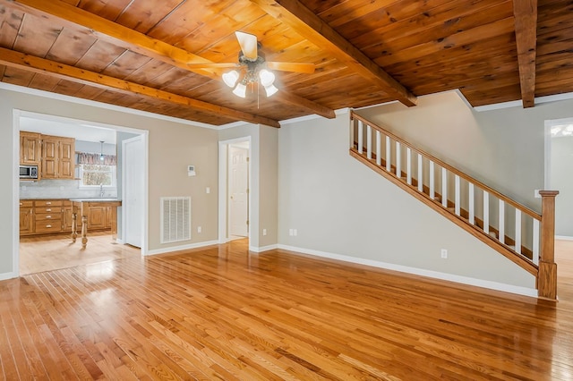 unfurnished living room with visible vents, wood ceiling, light wood-type flooring, beamed ceiling, and stairs