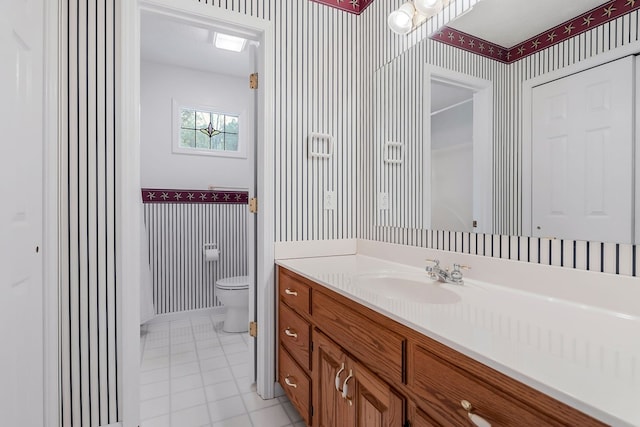 full bathroom featuring wallpapered walls, baseboards, toilet, tile patterned flooring, and vanity