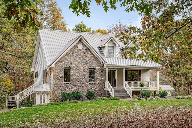 view of front of house featuring stone siding, metal roof, stairs, a porch, and a front yard