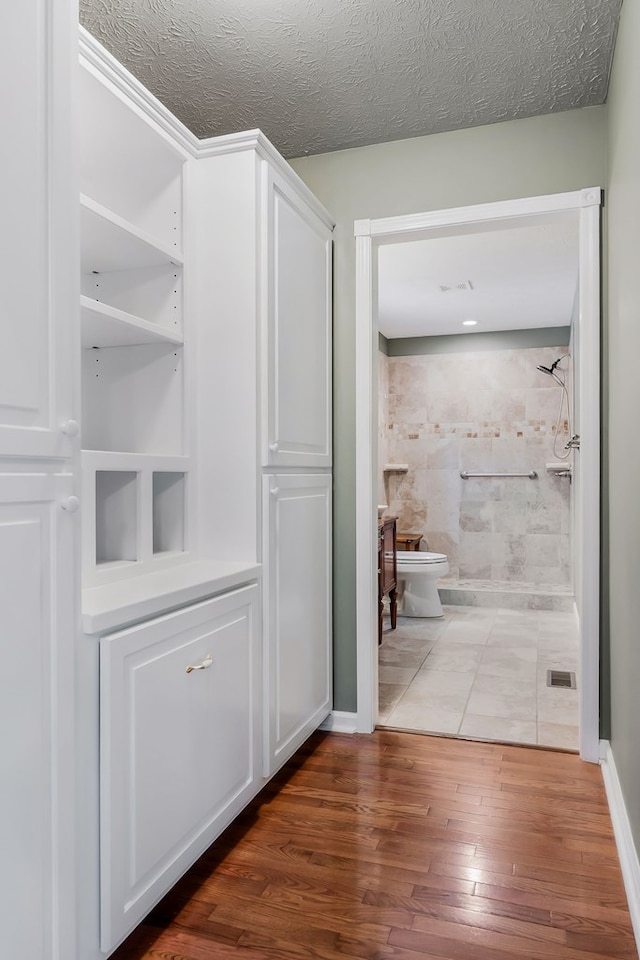 corridor featuring a textured ceiling and wood finished floors