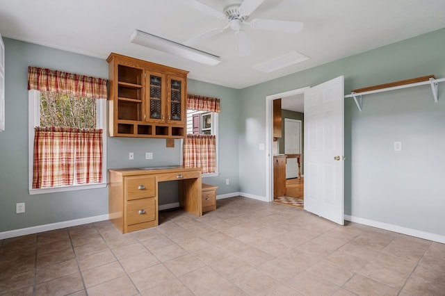 unfurnished office with baseboards, ceiling fan, and a healthy amount of sunlight