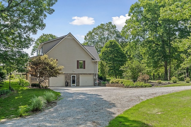 view of home's exterior featuring stone siding, metal roof, gravel driveway, an attached garage, and a yard