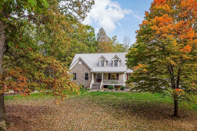 view of front of house featuring metal roof, stone siding, a porch, and a front yard