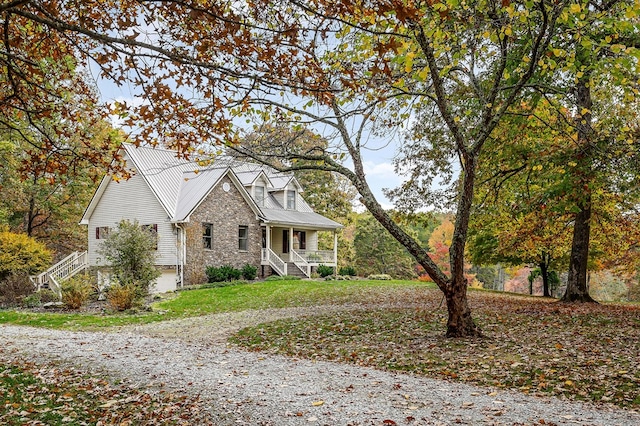 view of front of home featuring gravel driveway, metal roof, stairway, and a porch