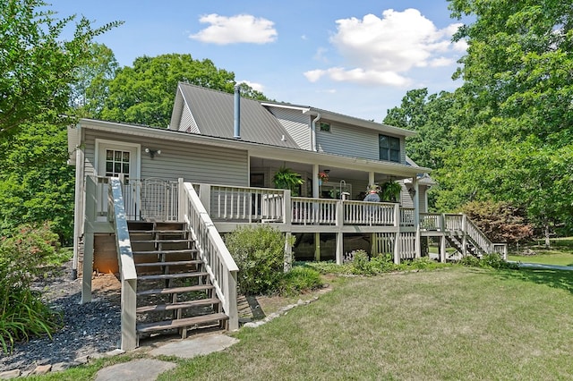 back of property with a wooden deck, stairway, metal roof, and a yard