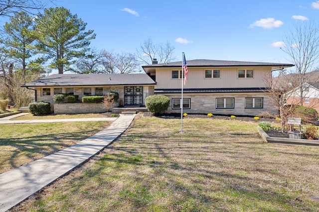 split level home featuring stone siding and a front lawn