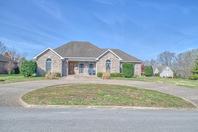 ranch-style house featuring brick siding, a front yard, and curved driveway