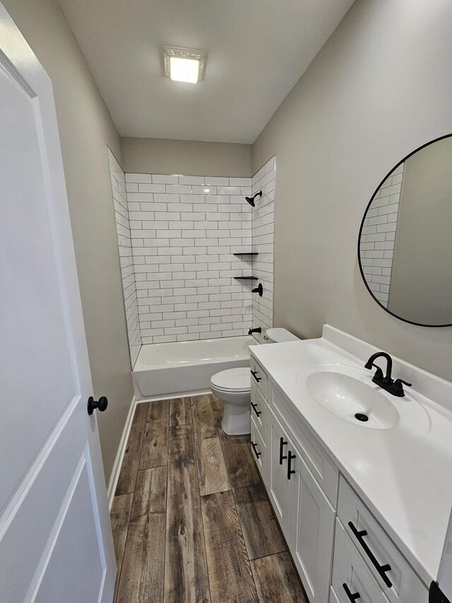 bathroom featuring shower / tub combination, toilet, wood finished floors, vanity, and baseboards