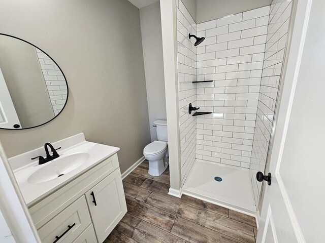 full bathroom with baseboards, toilet, wood finished floors, vanity, and a shower stall