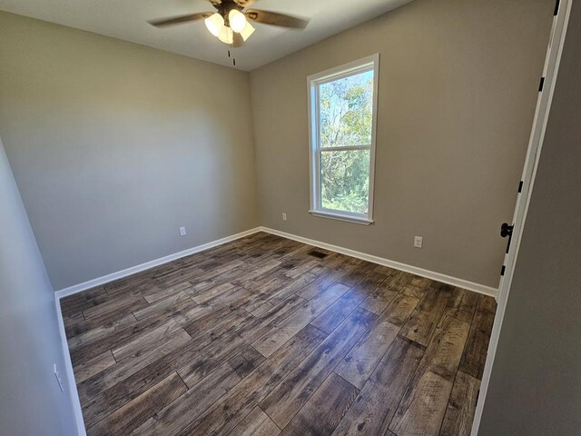 empty room featuring dark wood finished floors, a ceiling fan, and baseboards