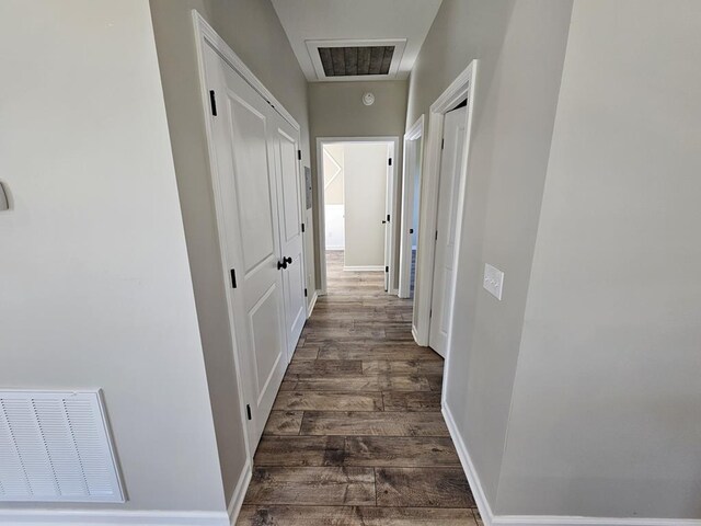 corridor featuring dark wood-type flooring, visible vents, and baseboards