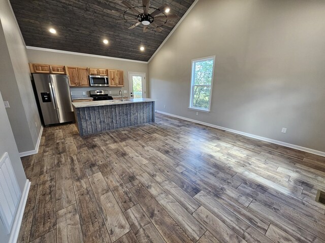 kitchen featuring open floor plan, wood finished floors, a kitchen island with sink, stainless steel appliances, and light countertops