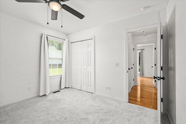 unfurnished bedroom featuring light carpet, visible vents, baseboards, ceiling fan, and a closet