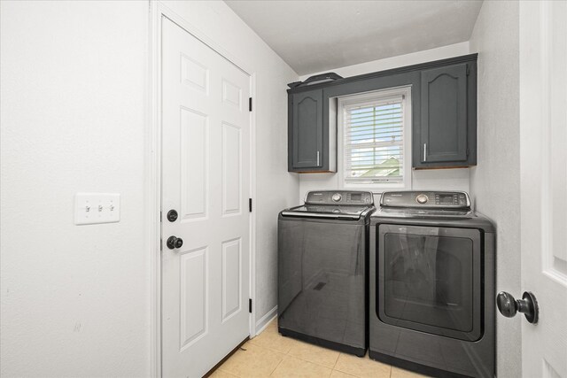 laundry area featuring washing machine and dryer, cabinet space, and light tile patterned floors