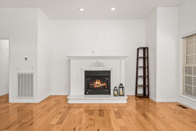 unfurnished living room featuring visible vents, wood finished floors, and a glass covered fireplace