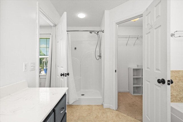 bathroom with a stall shower, tile patterned flooring, a spacious closet, and vanity