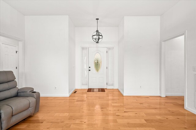 entrance foyer featuring a chandelier, light wood-type flooring, and baseboards