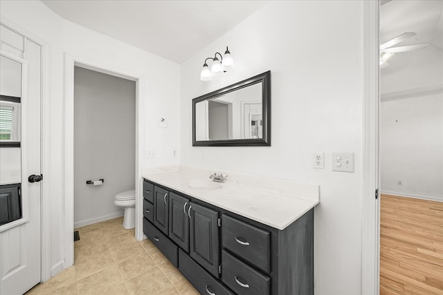 bathroom with tile patterned flooring, baseboards, vanity, and toilet