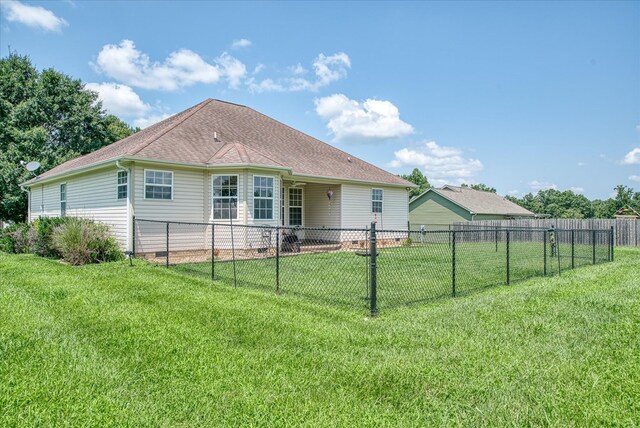 back of property featuring a shingled roof, a yard, and fence