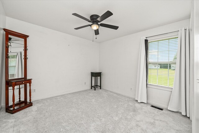 spare room featuring baseboards, a ceiling fan, visible vents, and light colored carpet