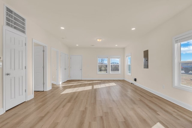 unfurnished living room with light wood-style flooring, electric panel, baseboards, and recessed lighting