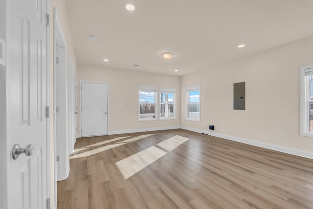 interior space with light wood-type flooring, electric panel, baseboards, and recessed lighting