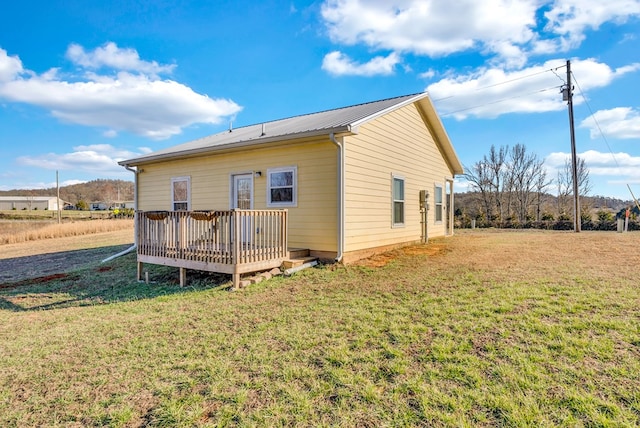 rear view of property with a wooden deck, metal roof, and a yard