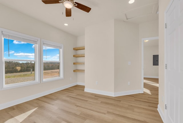 empty room featuring recessed lighting, attic access, light wood-type flooring, electric panel, and baseboards