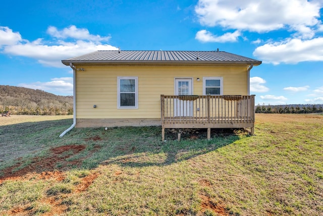 back of property with a standing seam roof, metal roof, a lawn, and a wooden deck