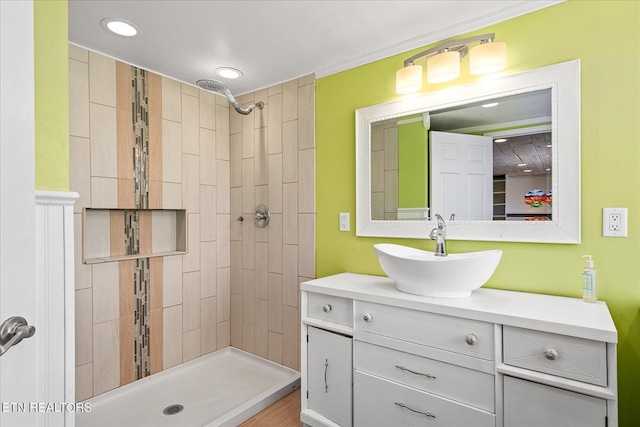 full bathroom with recessed lighting, a tile shower, vanity, and crown molding