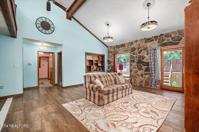 living area featuring baseboards, wood finished floors, a textured ceiling, high vaulted ceiling, and beam ceiling