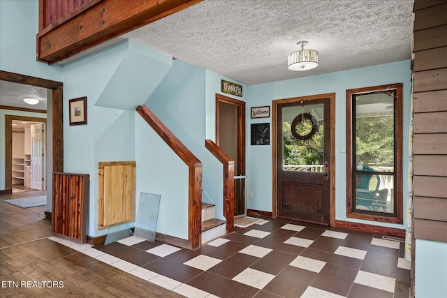 entrance foyer with baseboards, dark floors, stairway, and a textured ceiling